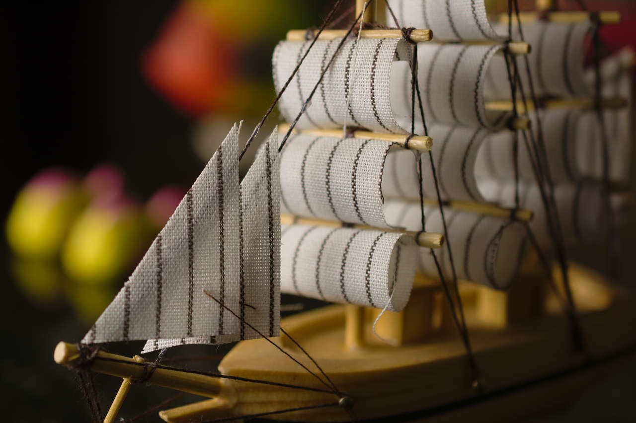 Profundidade de campo em fotografia de miniatura de barco, com vela em primeiro plano nítida e fundo desfocado.