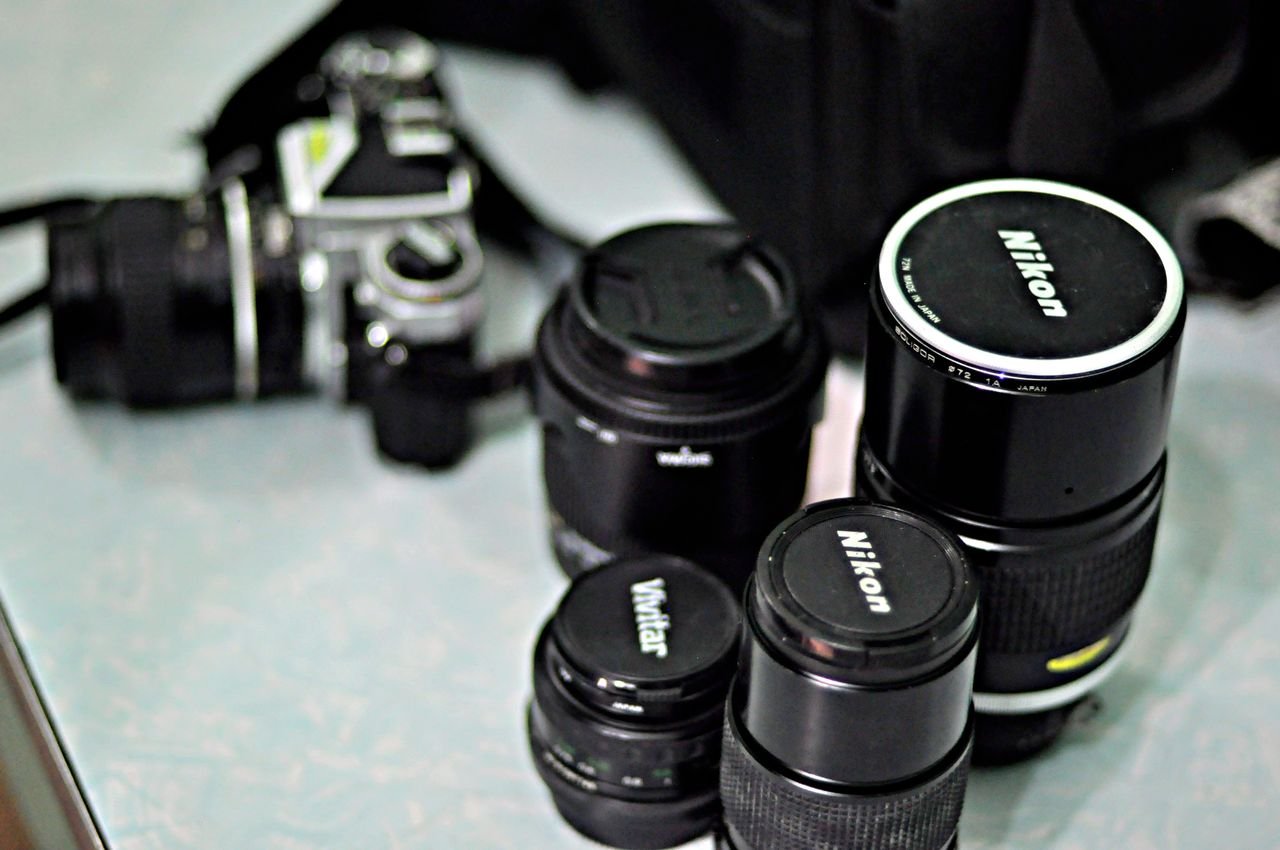 câmera Nikon com três lentes inctercambiáveis sobre a mesa, ilustrando artigo sobre lentes na fotografia