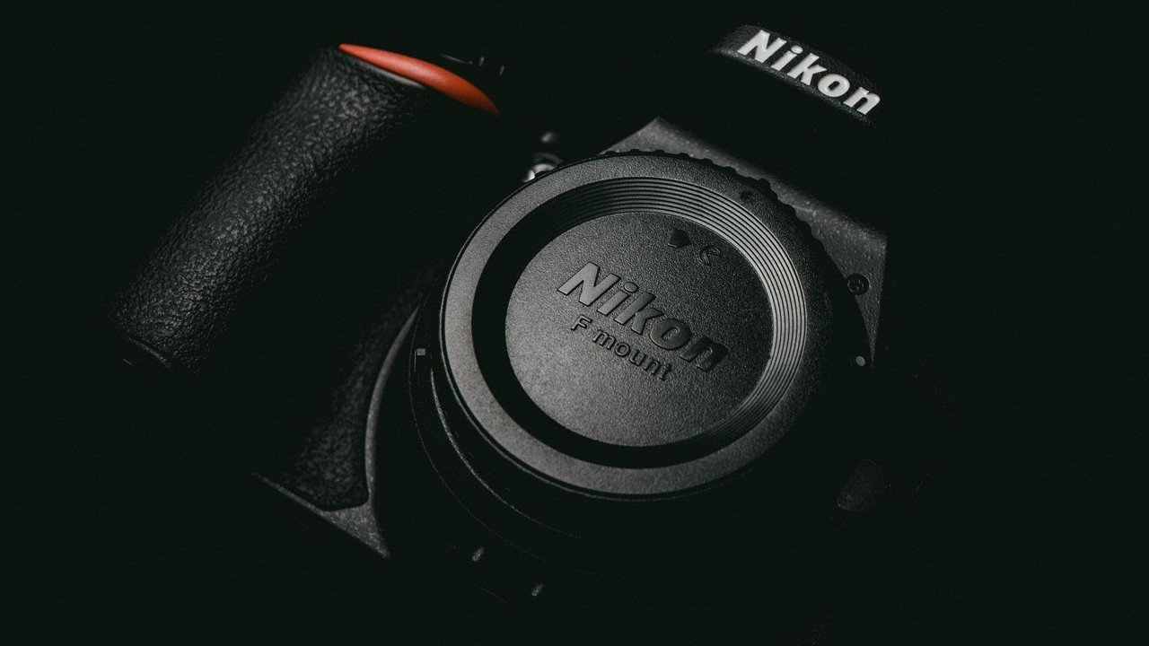Corpo de Câmera Nikon sem lente, com tampa para lente em ambiente de pouca luz, ilustrando artigo Câmeras Nikon hoje.