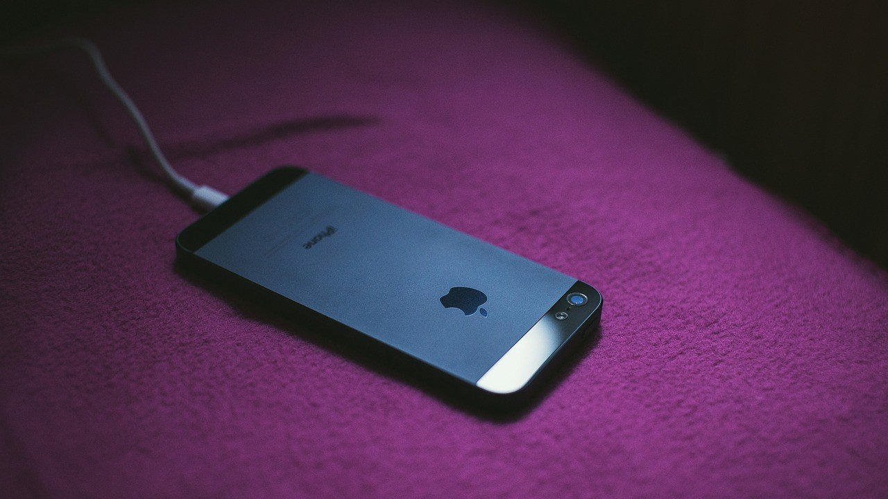 iPhone conectado ao carregador, imagem ilustrativa sobre carregar celular até 80% para preservar a bateria.