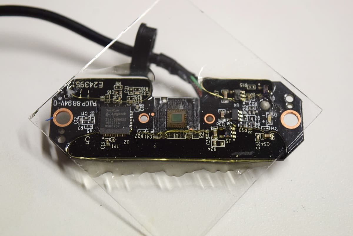 Placa de uma webcam Logitech C210 com o sensor CMOS exposto no centro, ilustrando artigo Fotografia digital: como a luz vira informação?
